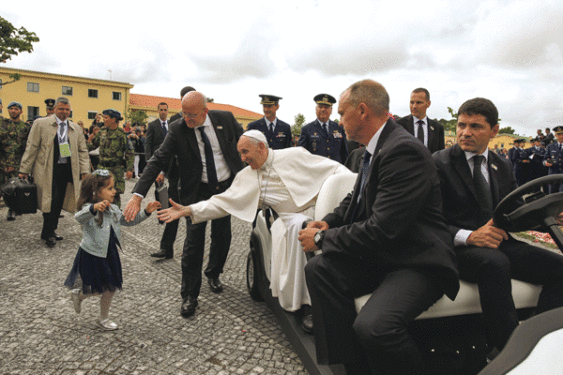 Pope Francis prays at the tomb of Fatima seer Francisco Marto before celebrating the canonization Mass for him and his sister, Jacinta Marto, at the Shrine of Our Lady of Fatima in Portugal, May 13. Below, Pope Francis greets a girl after arriving May 12 at Monte Real air base in Leiria, Portugal.  (CNSphoto/ Paulo Cunha, pool via Reuters)