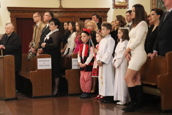 The congregation, including children dressed in traditional Polish garb, stand during the Eucharistic celebration commemorating the centennial anniversary of the parish and the silver anniversary of the  supplementary parochial Polish school.