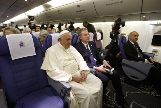 Pope Francis is seated during turbulence as he takes a break from answering questions aboard his flight from Lima, Peru, to Rome Jan. 21. Seated next to the pope is Greg Burke, Vatican spokesman. (CNS photo/Paul Haring)