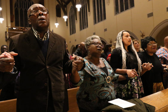 People hold hands and sing during the prayer service remembering King. (CNS photo/Gregory A. Shemitz, Long Island Catholic) 