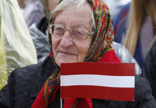 An elderly woman holds the Latvian flag as Pope Francis celebrates Mass Sept. 24 at the Shrine of the Mother of God in Aglona, Latvia. (CNS photo/Paul Haring)