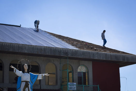 In this 2014 file photo, men replace the roof of Assumption Academy in Tanauan, Philippines, To date, the social action arm of the Catholic Church has been able to help about 1.8 million people affected by the destruction brought byr Typhoon Haiyan that struck the central Philippines in 2013. (CNS photo/Tyler Orsburn) 